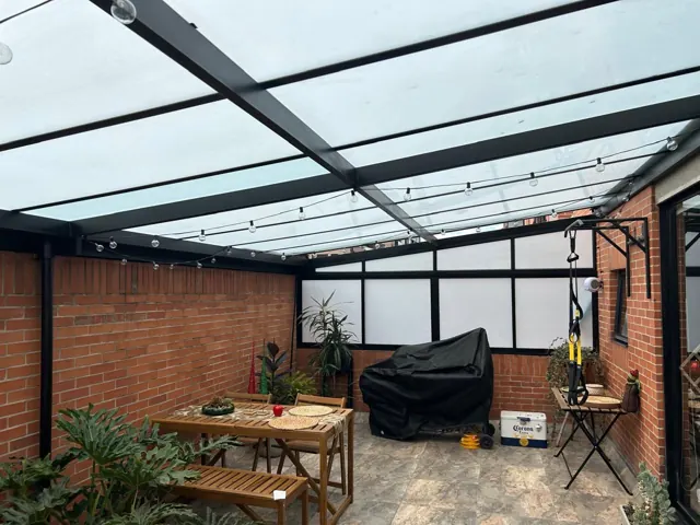 Cerramiento de terraza con marquesina en vidrio y estructura negra — Bogotá