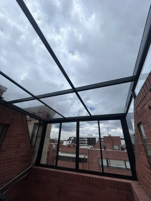 Marquesina en vidrio sobre terraza con muro en ladrillo — Bogotá