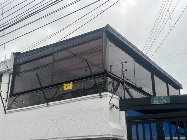 Marquesina en vidrio sobre balcón en fachada de vivienda — Bogotá