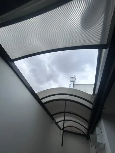 Marquesina curva en policarbonato sobre entrada exterior — Bogotá