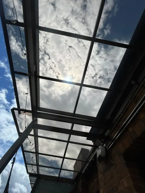 Marquesina en vidrio sobre corredor exterior con vista al cielo — Bogotá