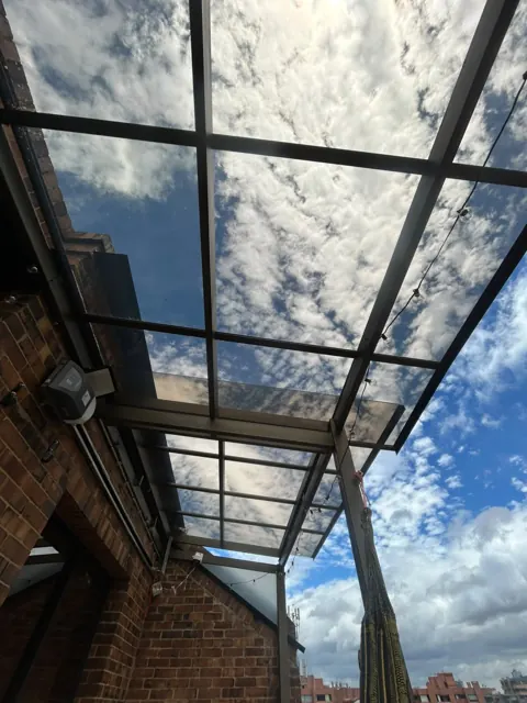 Marquesina en vidrio entre muros en ladrillo con vista al cielo — Bogotá