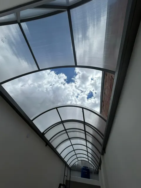 Marquesina curva en policarbonato sobre corredor exterior — Bogotá