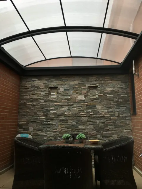 Marquesina en policarbonato sobre barra exterior con muro en piedra — Bogotá