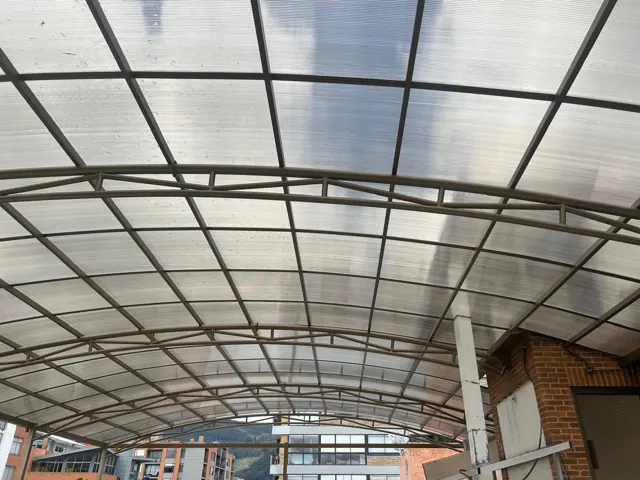 Marquesina curva en policarbonato sobre terraza con reja — Bogotá