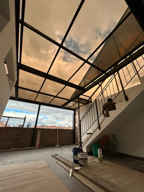 Marquesina en vidrio con estructura metálica negra sobre terraza en obra — Bogotá