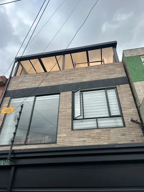 Cerramiento de terraza en vidrio y estructura negra en fachada de edificio en ladrillo — Bogotá