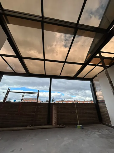 Marquesina en vidrio con estructura negra sobre terraza con vista a la ciudad — Bogotá