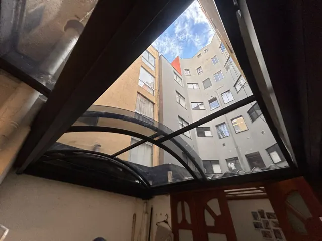 Marquesina curva en policarbonato sobre patio interior de edificio — Bogotá