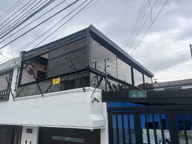 Marquesina en vidrio sobre terraza de vivienda de dos pisos — Bogotá