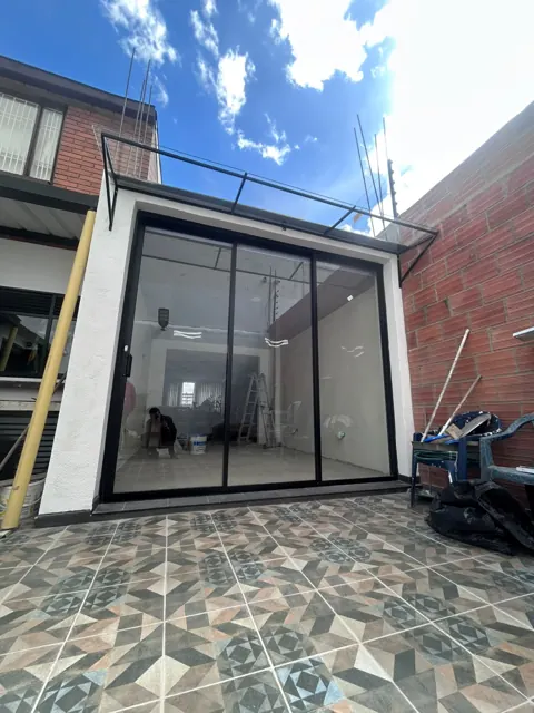 Cerramiento en vidrio y aluminio negro en patio con piso decorativo — Bogotá
