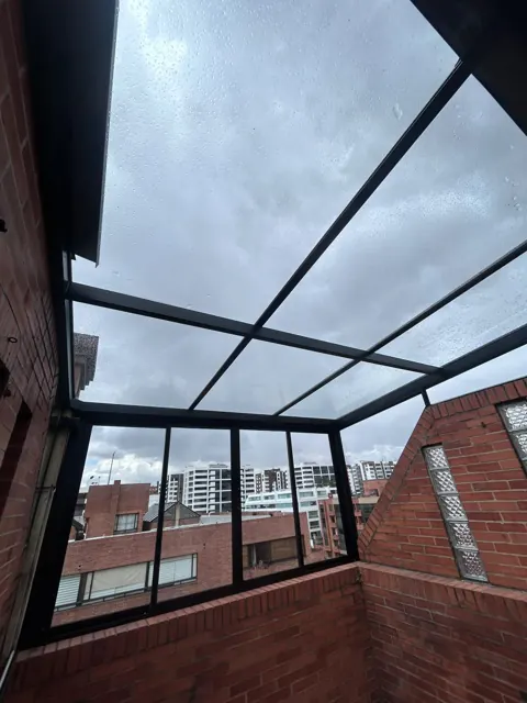 Marquesina en vidrio entre muros en ladrillo sobre terraza — Bogotá